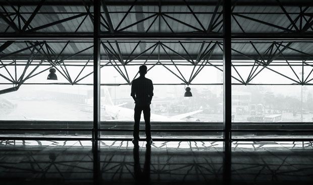 A man looking out of an airplane hanger onto the runway